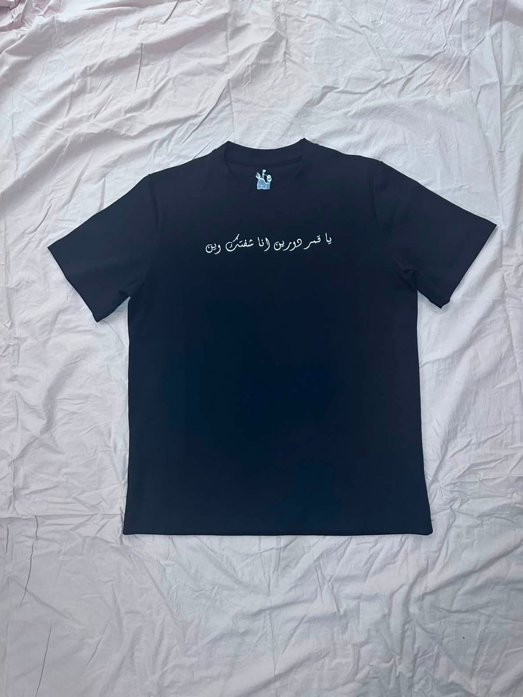 Black basic Tee with arabic text embroidered on chest and small logo embroidered on back below neck